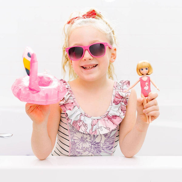 Girl holding Strawberry Blonde Lottie in Swimsuit, yellow floaties, and towel and inflatable flamingo