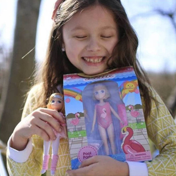 Girl holing box with Strawberry Blonde Lottie in Swimsuit, yellow floaties, and towel and inflatable flamingo