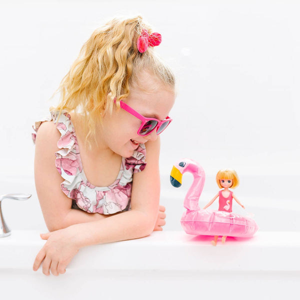 Girl looking at Strawberry Blonde Lottie in Swimsuit, yellow floaties, and towel and inflatable flamingo