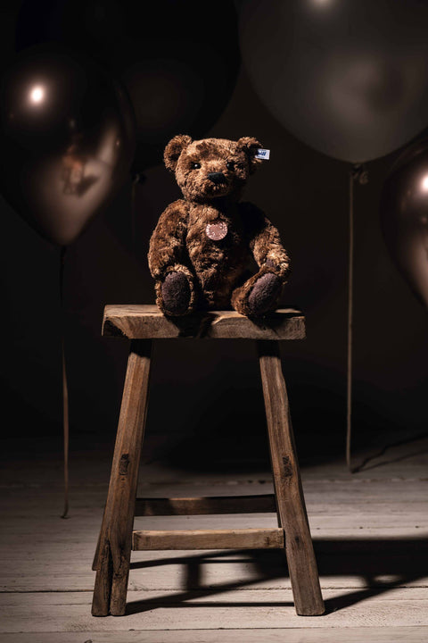 Brown teddy sitting on a stool