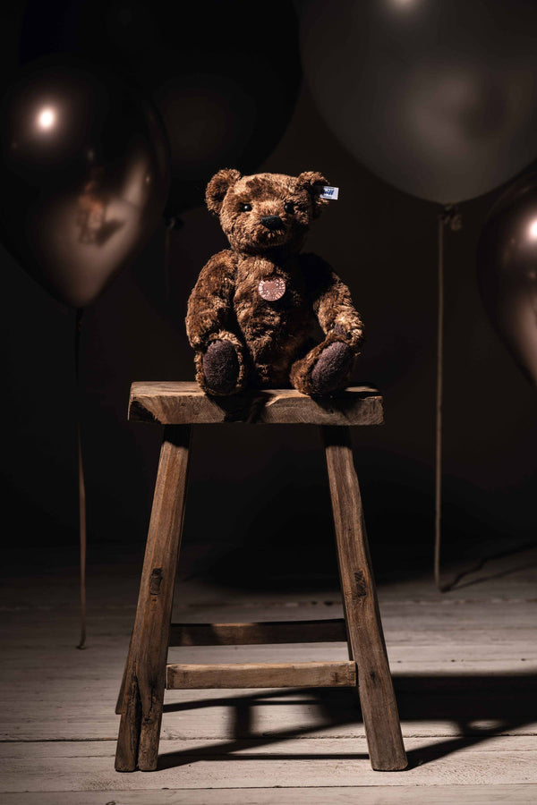 Brown teddy sitting on a stool