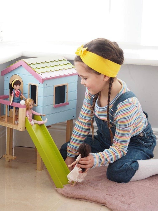 Girl playing with Lottie Doll with Dark brown hair. in white leggings and jean skirt and red/white stripe shirt