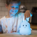 Boy touching the White lumipet Penguin with remote as it is lit up light blue