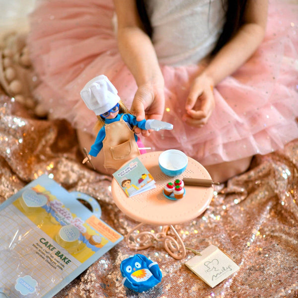 Chid playing with doll and Doll apron, mixing bowl, chef hat, mitt, rolling pin, spoon, cupcakes and recipe book